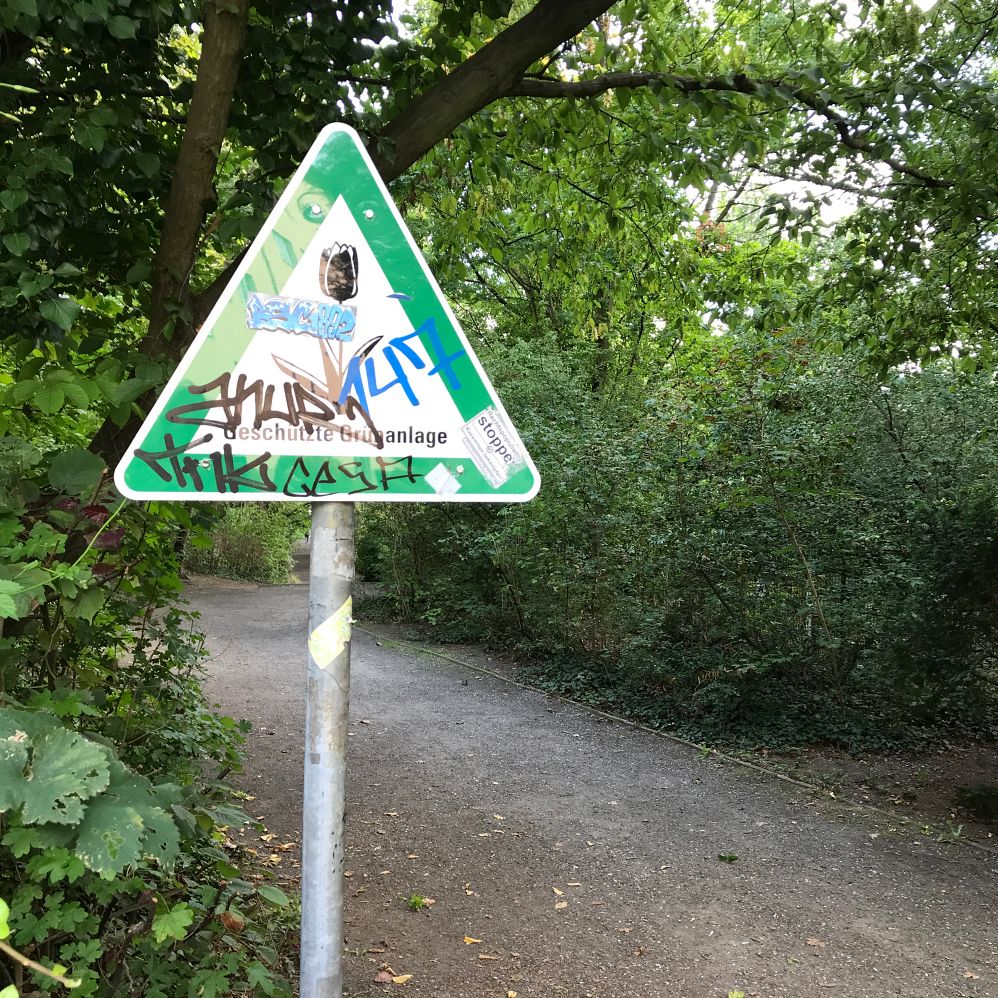Schild geschützte Grünanlage mit Graffiti